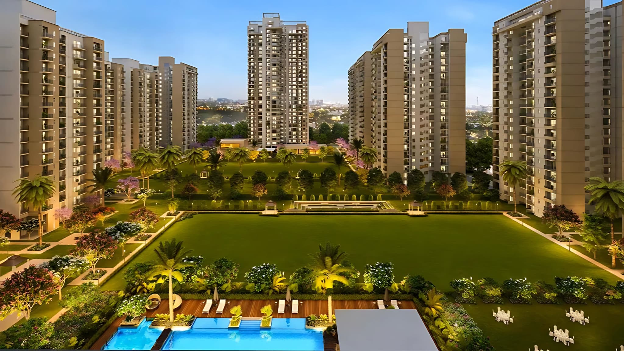Luxury residential apartments with illuminated landscaped gardens, central green lawn, swimming pool, and modern high-rise towers at dusk